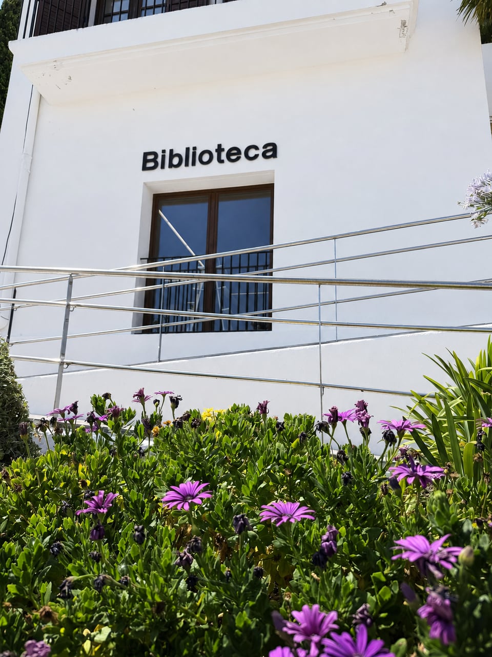 Façana de la biblioteca amb la rampa d’accés i flors